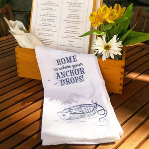 Tea towel home is where your anchor drops on wooden table beside menu