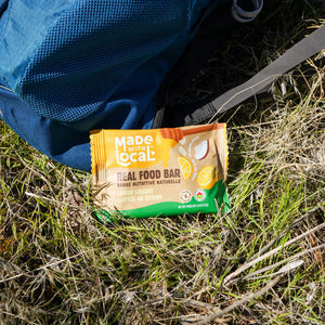 Made with Local lemon square real food bar beside backpack