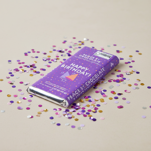 happy birthday peace by chocolate bar on table surrounded by confetti