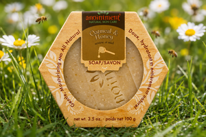 Anointment Oatmeal and Honey Soap in the grass with bees and flowers in the background