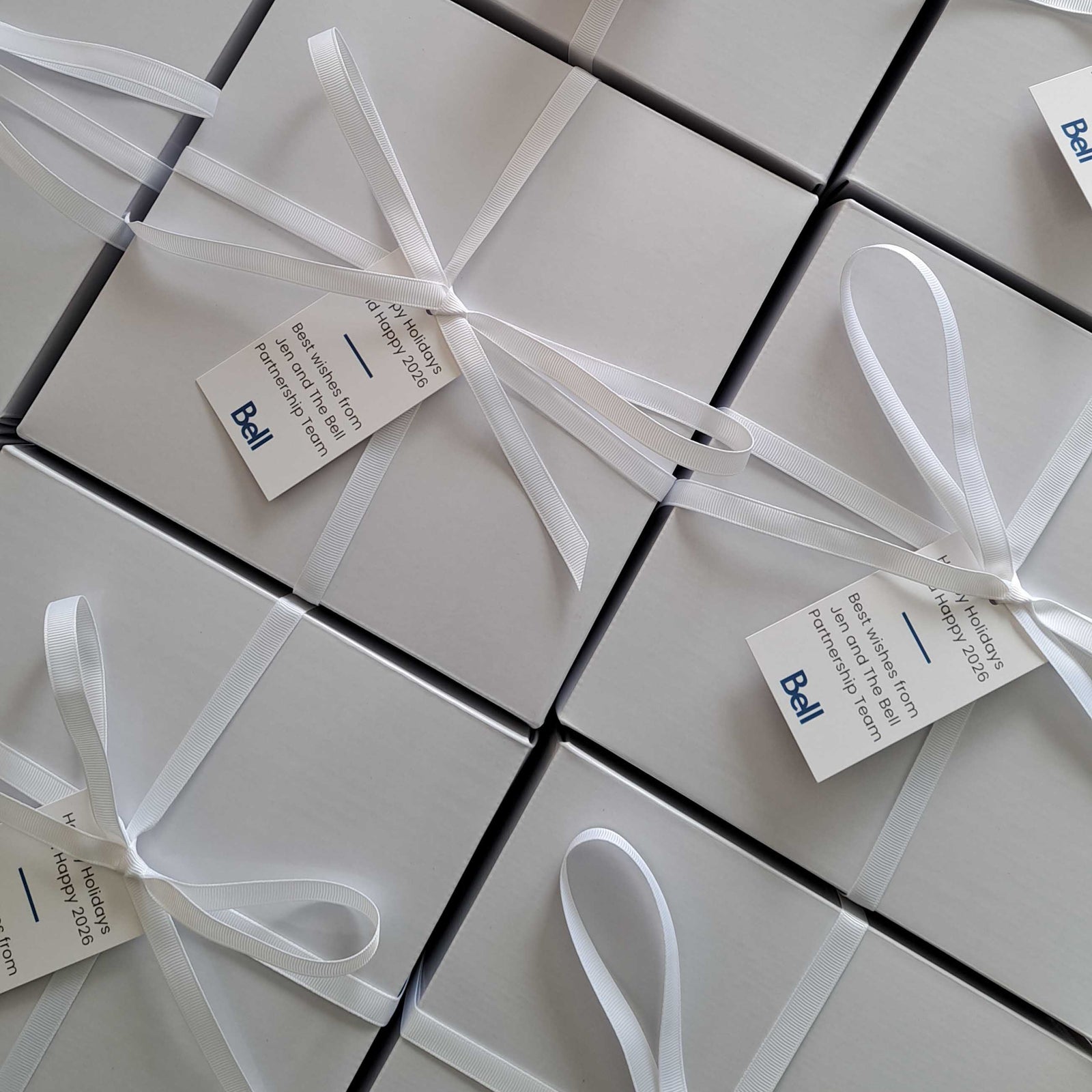 White corporate gift boxes with white ribbon and Bell branded gift tags prepared for client and employee gifts