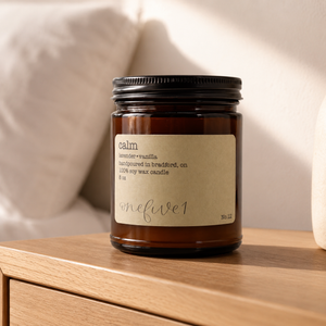 Soy candle labeled 'calm' on a wooden table with a bed in the background