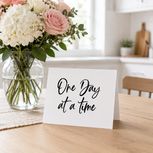 One Day at a Time card Pretty by Her on kitchen table with flowers