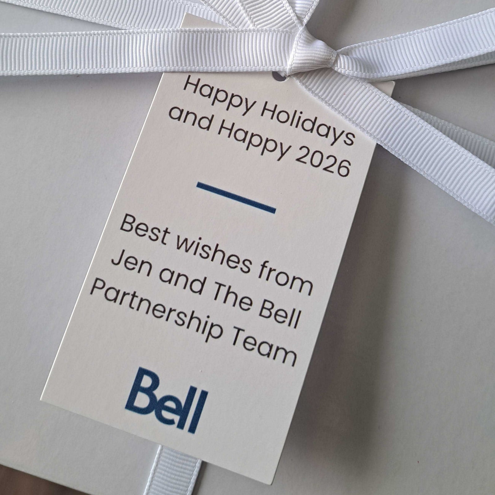 Close-up of a holiday corporate gift box with white ribbon and Bell branded gift tag for employee appreciation