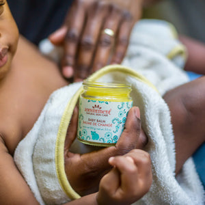 Anointment Baby Balm in man's hands while he holds baby