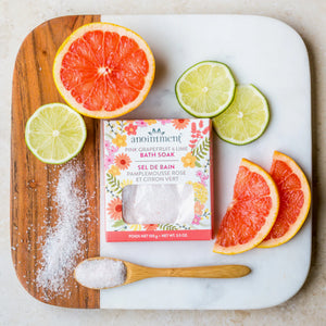 Anointment Pink Grapefruit and Lime Bath Soak surrounded by lime and grapefruit slices