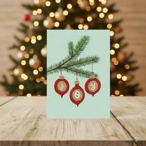 Joy Christmas Card in front of Christmas tree background