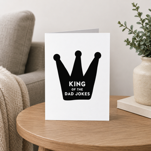 King of the Dad Jokes card Pretty by Her on end table beside couch