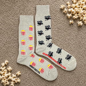 Women's camera and popcorn socks Friday Sock Co. on carpet with spilled popcorn